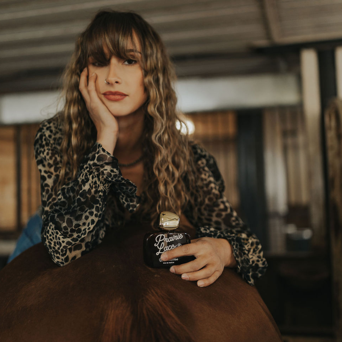 Woman holding Prairie Lace perfume by Western Hive, a feminine western fragrance inspired by prairie wildflowers and vanilla